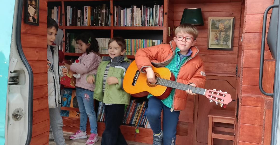 criancas dentro da carrinha e um menino com uma viola